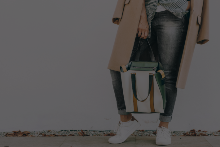 Lady standing with purse against a wall.